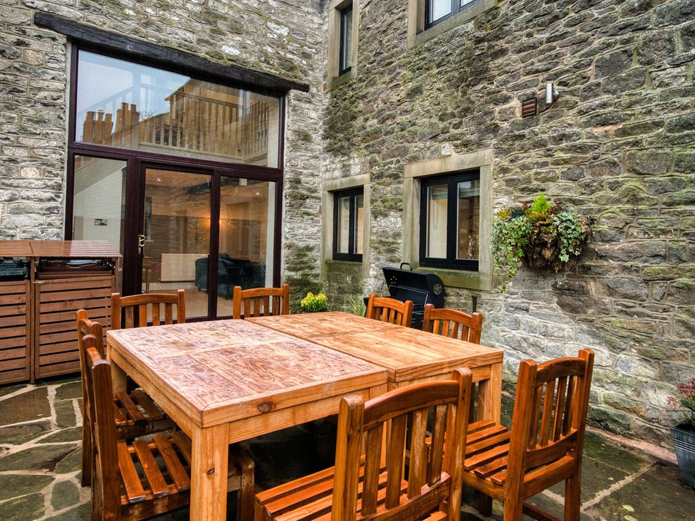 An outdoor dining area with a wooden table and chairs at The Forge in Castleton, Peak District
