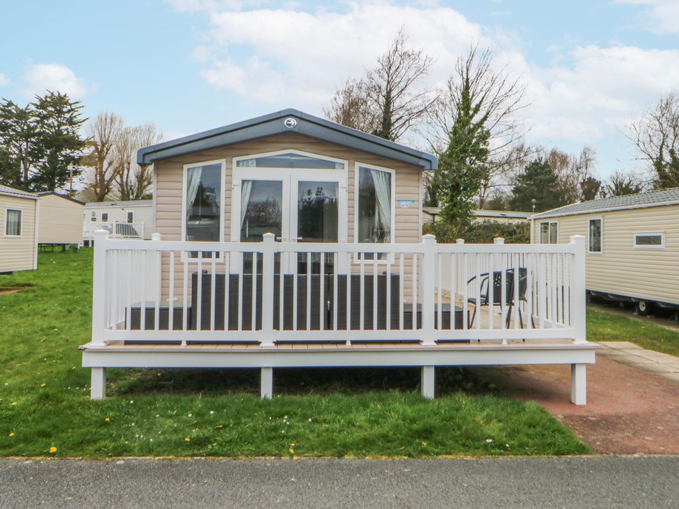 A caravan with a deck and railing at 49 Cader Idris, Hafan-Y-Mor Holiday Park in Pwllheli