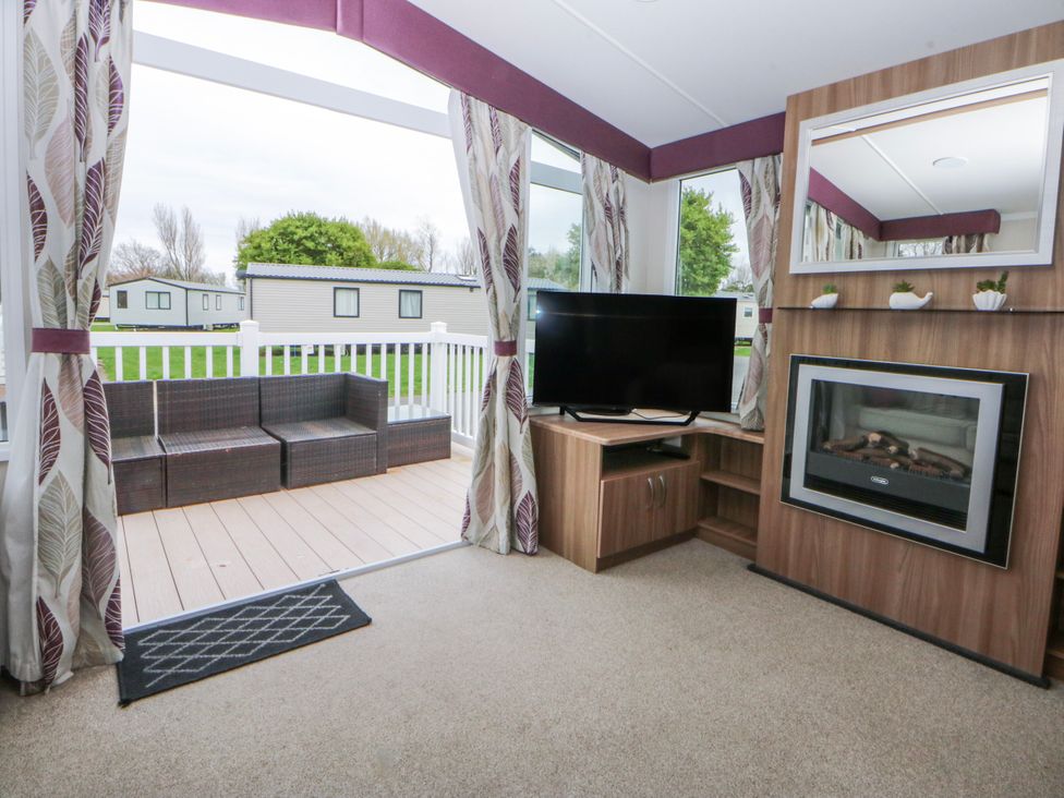 A living room with a sofa and television at 49 Cader Idris, Hafan-Y-Mor Holiday Park Pwllheli