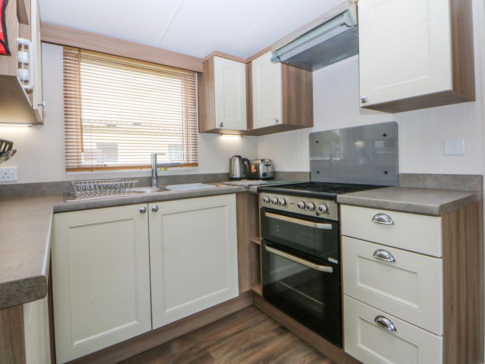 A kitchen with cabinets and appliances at 49 Cader Idris, Hafan-Y-Mor Holiday Park Pwllheli