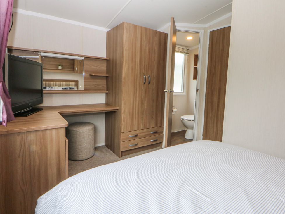 A bedroom with a television and a desk at 49 Cader Idris, Hafan-Y-Mor Holiday Park Pwllheli
