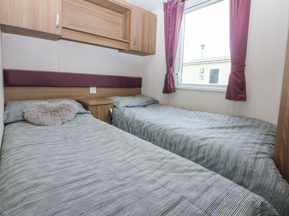 A bedroom with two beds and a window at 49 Cader Idris, Hafan-Y-Mor Holiday Park, Pwllheli