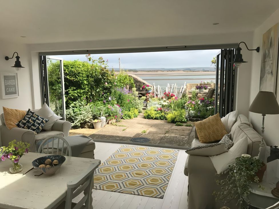 A living room with a sofa and table overlooking a garden at Mariners Cottage in Bideford