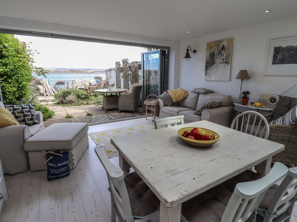 A living room with a dining table and view of the outdoor patio at Mariners Cottage in Bideford