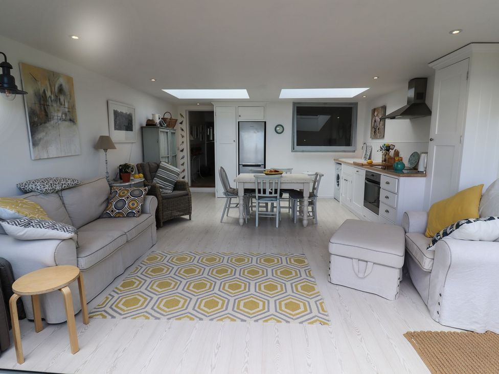 A living room with a sofa and dining area at Mariners Cottage in Bideford