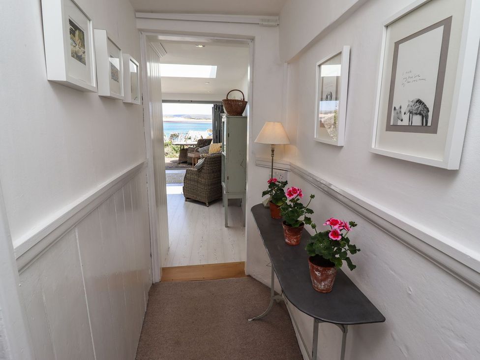 A hallway with flower pots and pictures at Mariners Cottage in Bideford