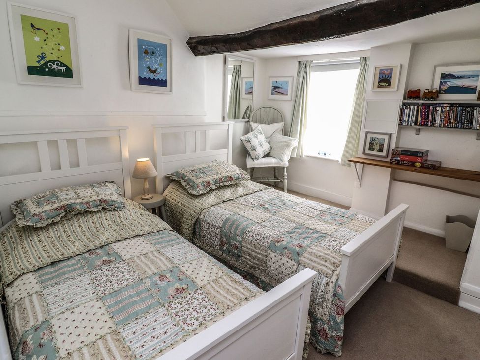 A bedroom with two single beds and a bookshelf at Mariners Cottage in Bideford