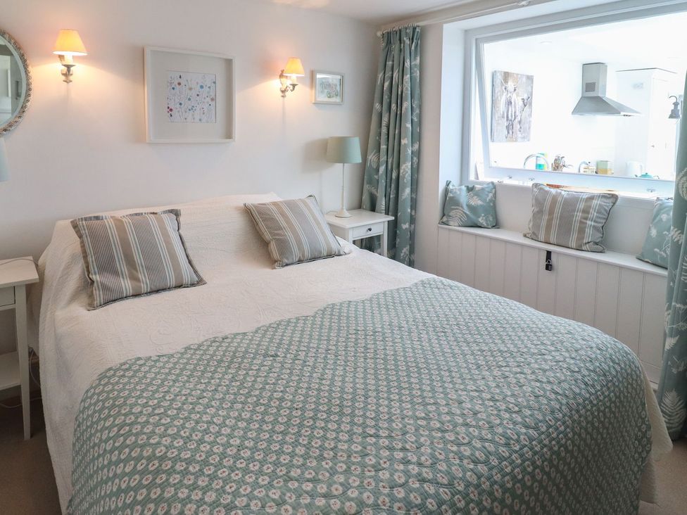 A bedroom with a bed and light fixtures at Mariners Cottage in Bideford
