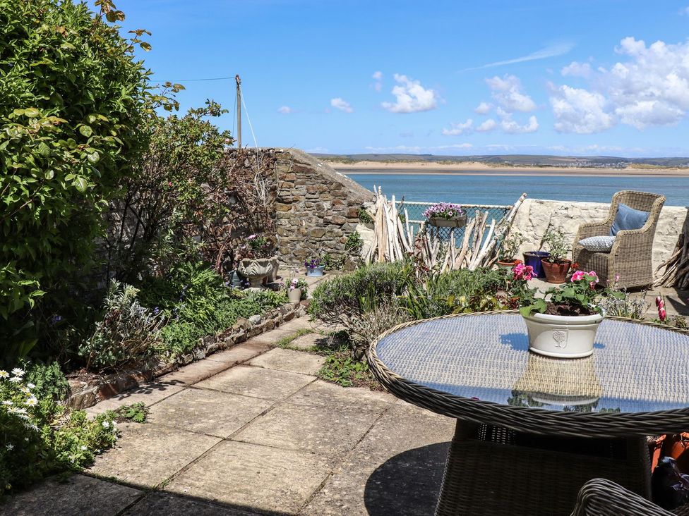 A garden with a table and chair overlooking the water at Mariners Cottage in Bideford