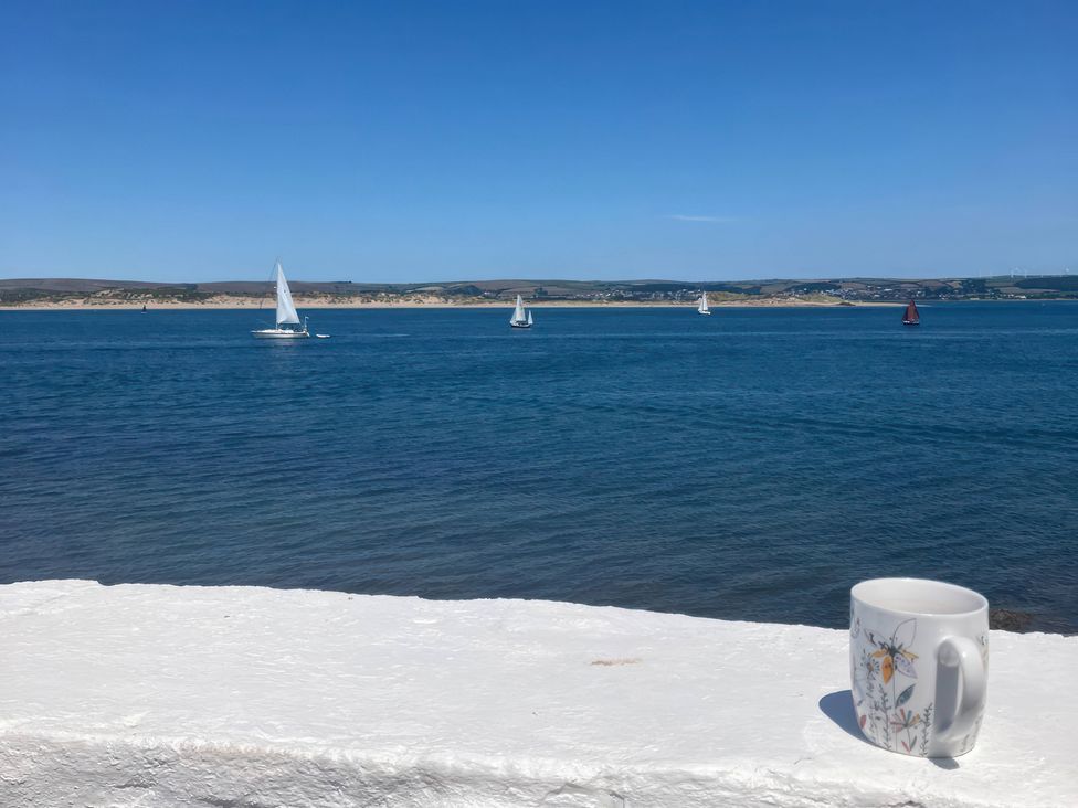 A view of sailing boats on the water with a mug on the shore at Mariners Cottage in Appledore