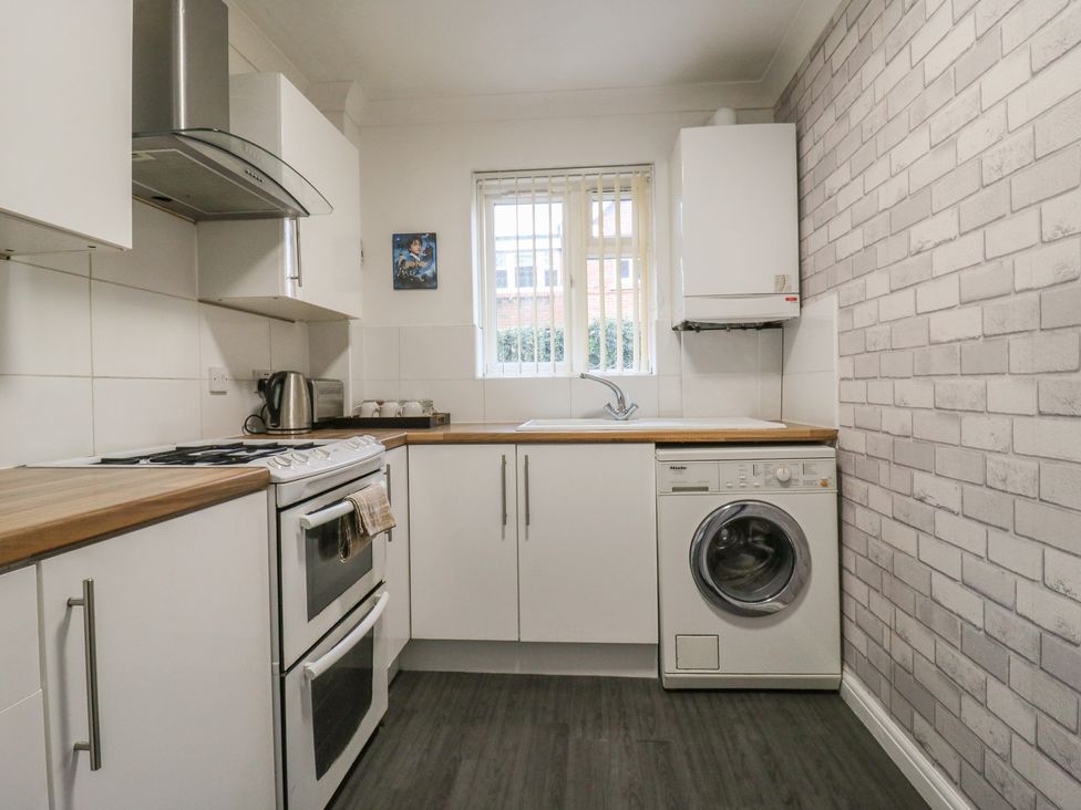 A kitchen with appliances including a stove and washing machine at Wizard's Hideaway in Watford