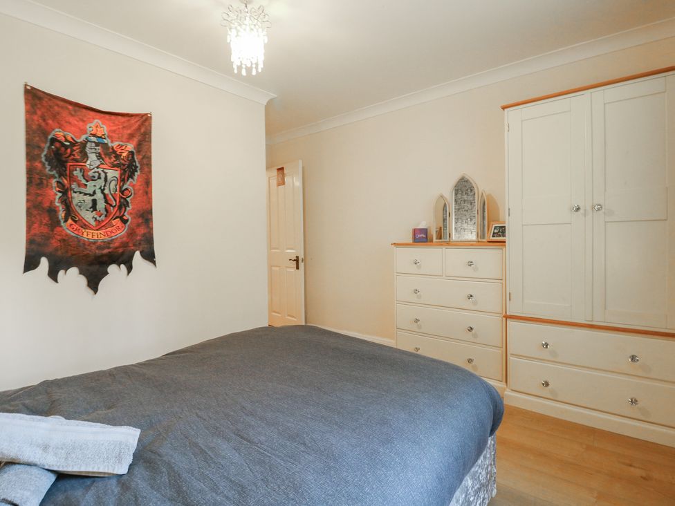 A bedroom with a grey bed and a Gryffindor wall decoration at Wizard's Hideaway in Watford