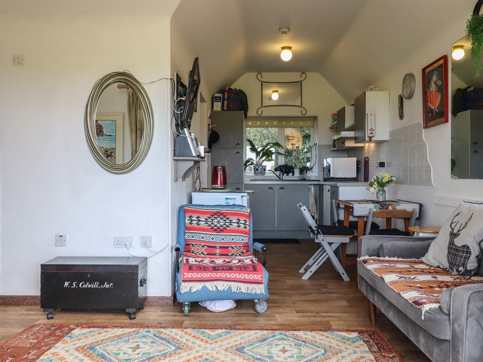 A living room with a mirror and kitchen area at The Old Telephone Exchange in Exeter