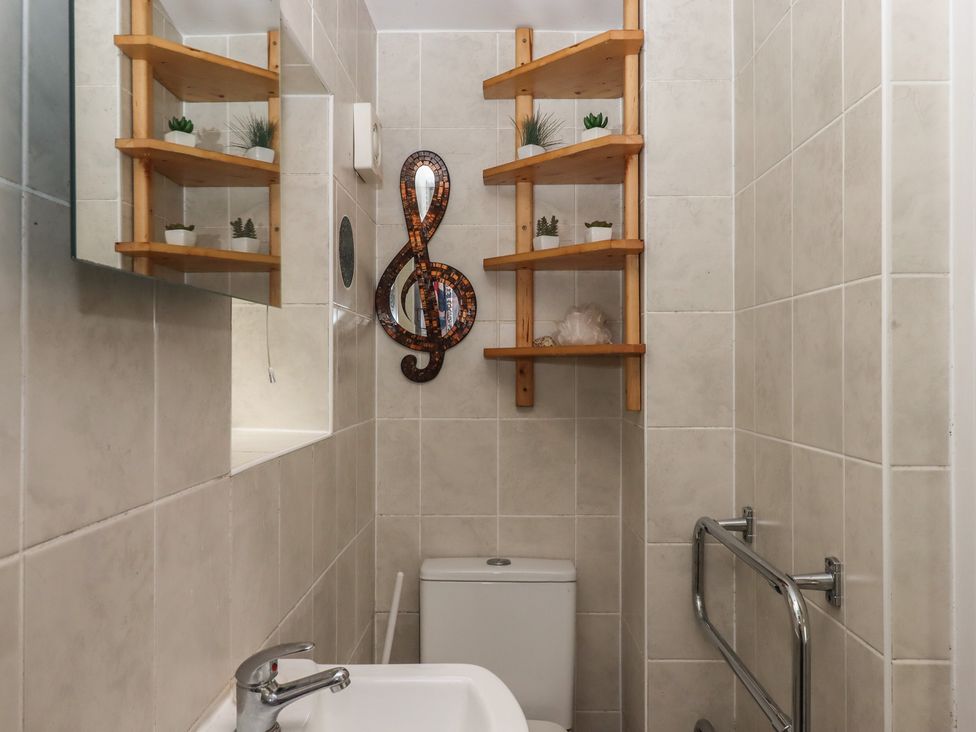 A bathroom with a sink, toilet, and shelving at The Old Telephone Exchange in Exeter