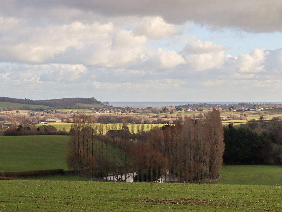 A landscape view with fields, trees, and a body of water at The Old Telephone Exchange in Exeter
