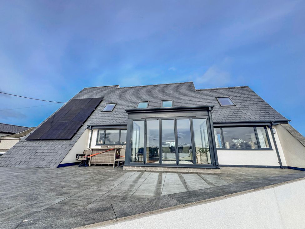 A modern building with solar panels and patio at Pengarnedd Amlwch