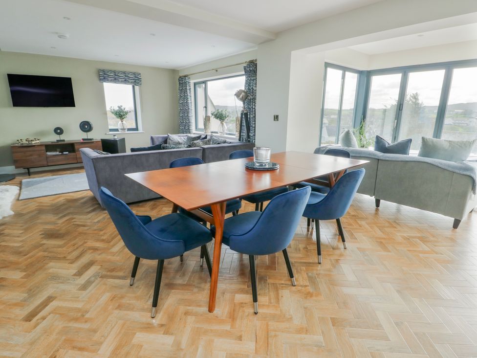 A living room with a dining area and large windows at Pengarnedd Amlwch