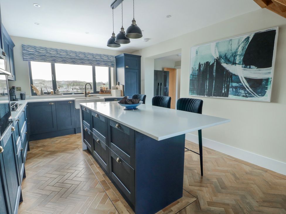 A kitchen with an island and bar stools at Pengarnedd Amlwch