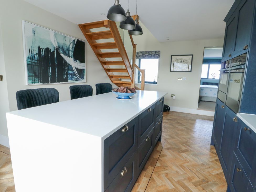 A kitchen with a table and chairs and a staircase at Pengarnedd in Amlwch