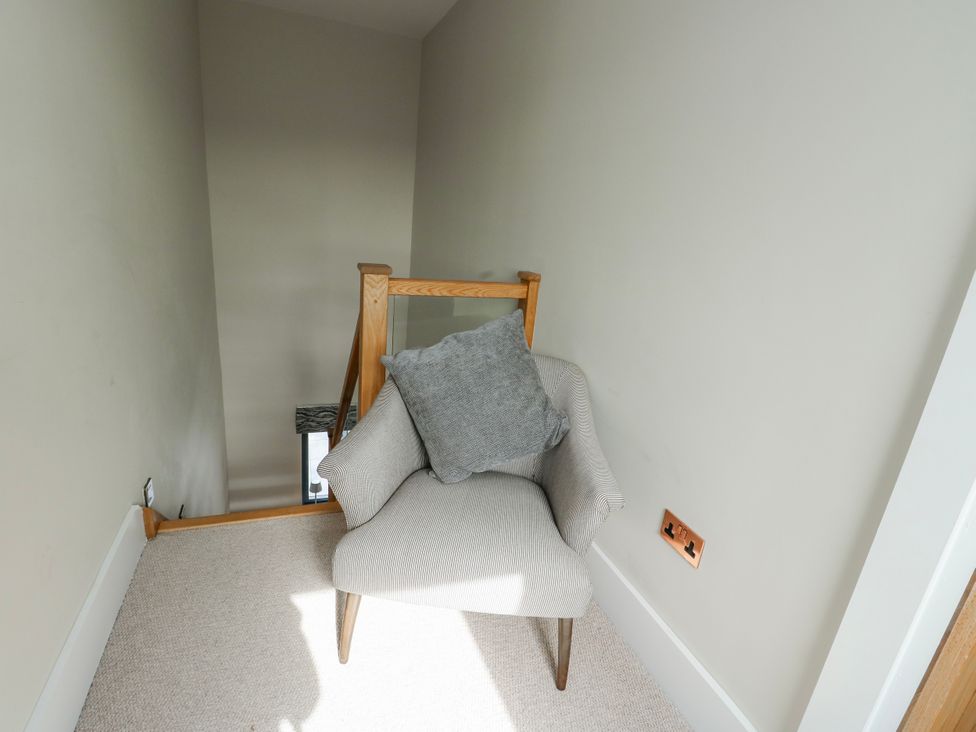 A chair on a landing area with a view of staircase at Pengarnedd in Amlwch