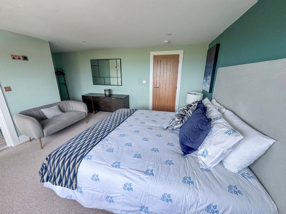 A bedroom with a bed and sofa at Pengarnedd in Amlwch