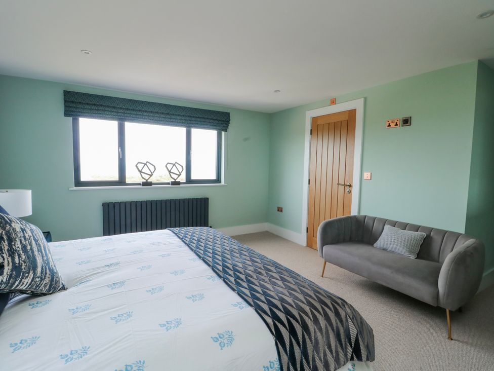 A bedroom with a bed and a sofa at Pengarnedd in Amlwch