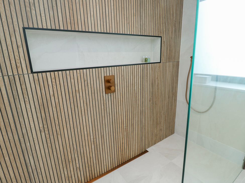 A shower area with wood paneling and shower controls at Pengarnedd in Amlwch