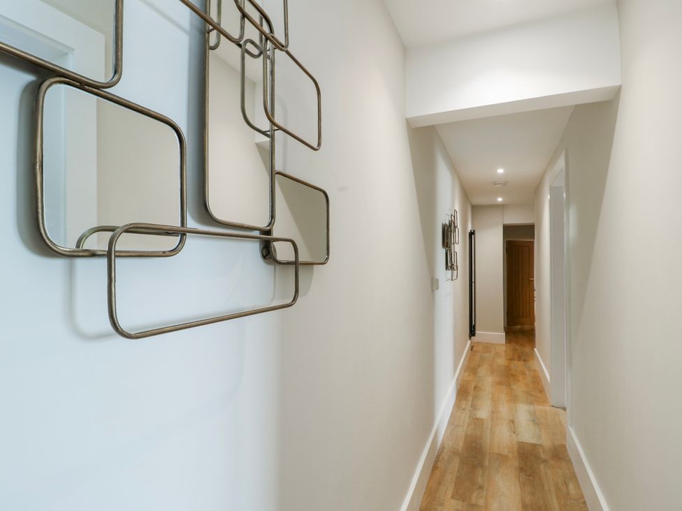 A hallway with mirrors and wooden floor at Pengarnedd in Amlwch