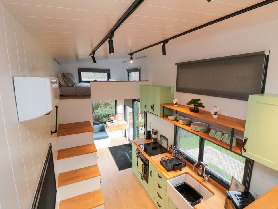 A kitchen with shelves and a loft bed at The Tiny Home