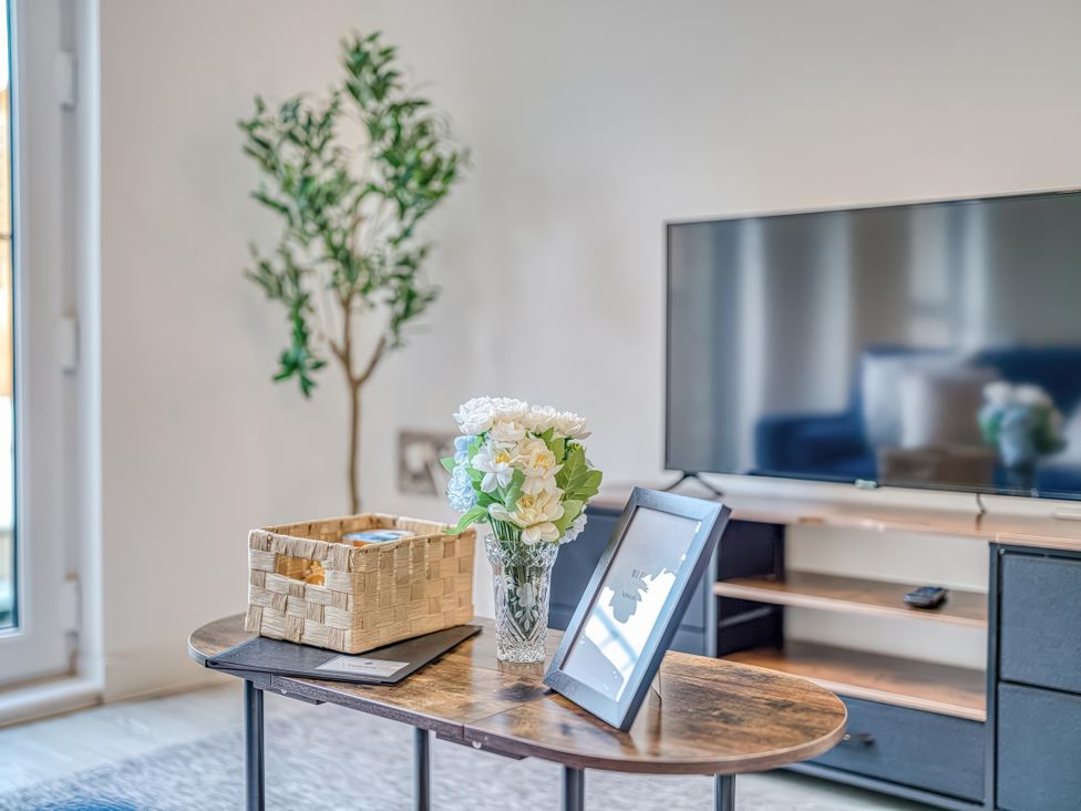 A living room with a table, flowers, and a television at Apartment 422 in Manchester