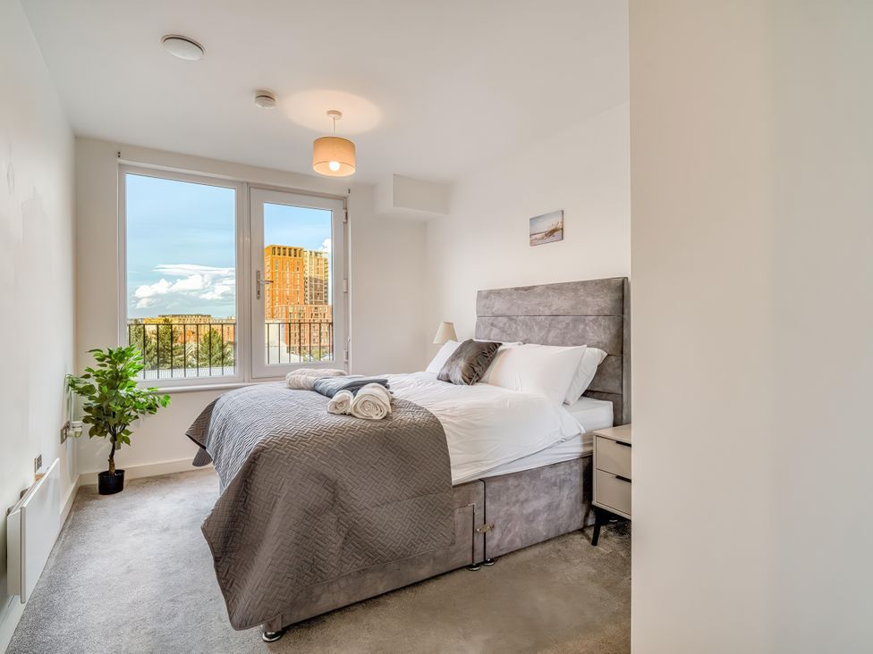 A bedroom with a bed and windows at Apartment 422 in Manchester