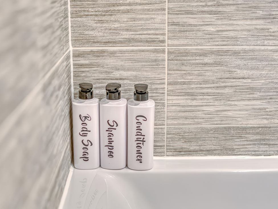 Bottles of body soap, shampoo, and conditioner in a bathroom at Apartment 422 in Manchester