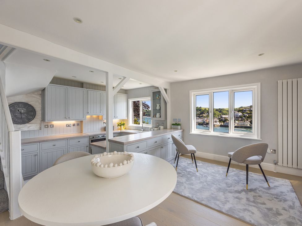 A kitchen with cabinets and a round table at Bell Cottage in Dartmouth