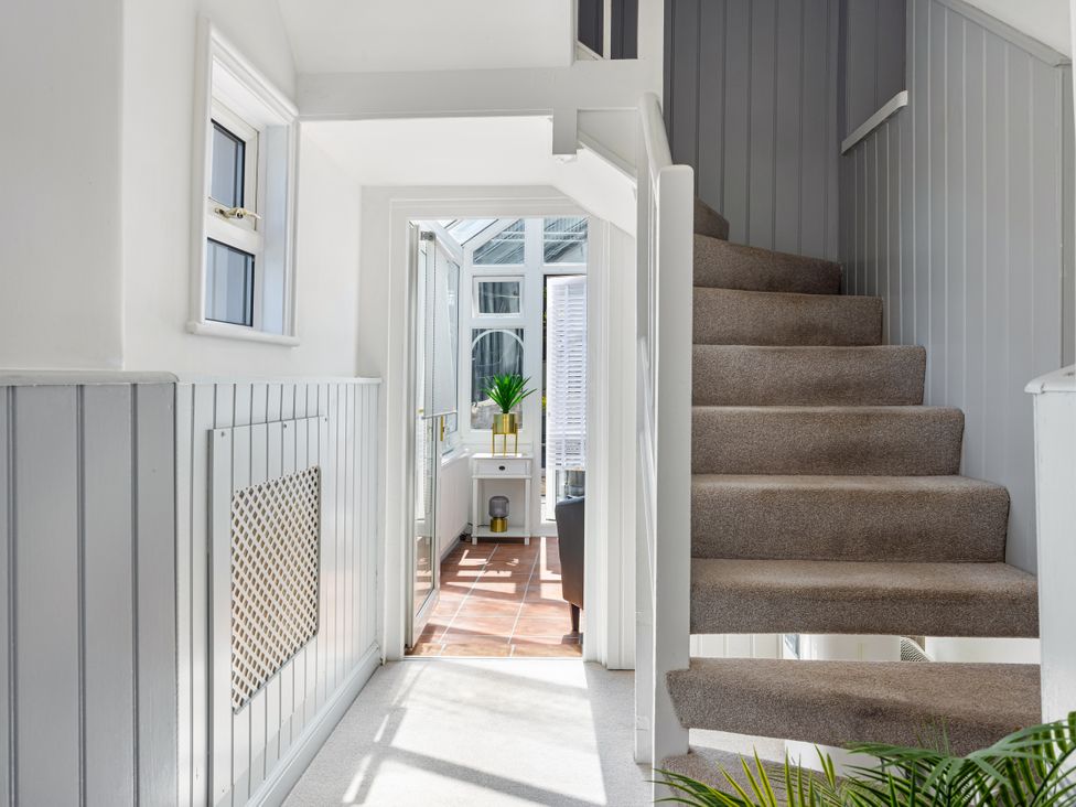 A hallway with a staircase and a door to a conservatory at Bell Cottage Dartmouth
