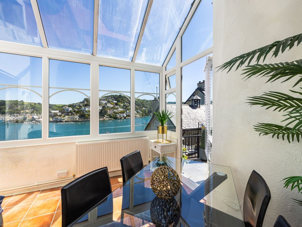 A conservatory with a glass table and black chairs at Bell Cottage in Dartmouth