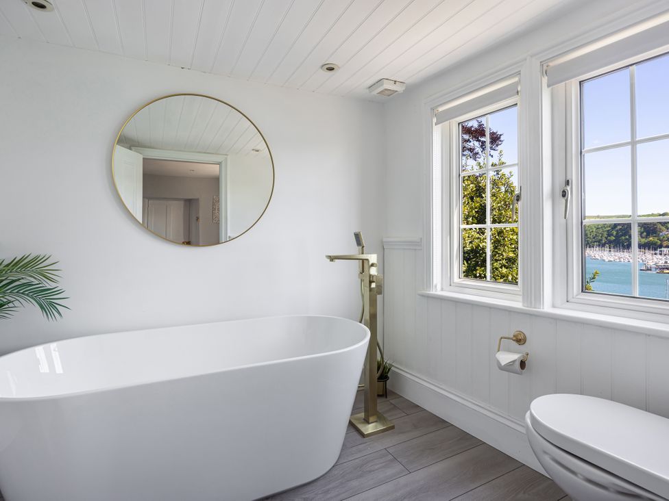A bathroom with a bathtub, toilet, and windows at Bell Cottage in Dartmouth