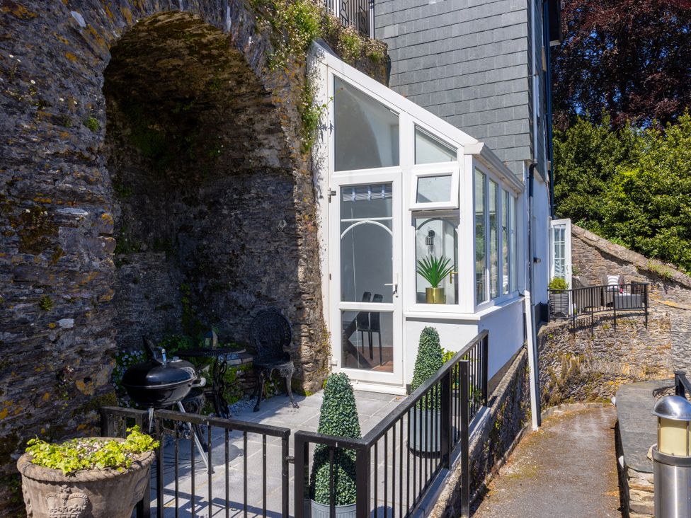 An outdoor patio with a stone wall and seating at Bell Cottage Dartmouth