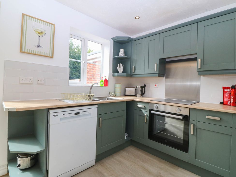 A kitchen with green cabinets, sink, oven and kettle at Meadow View in Kinmel Bay