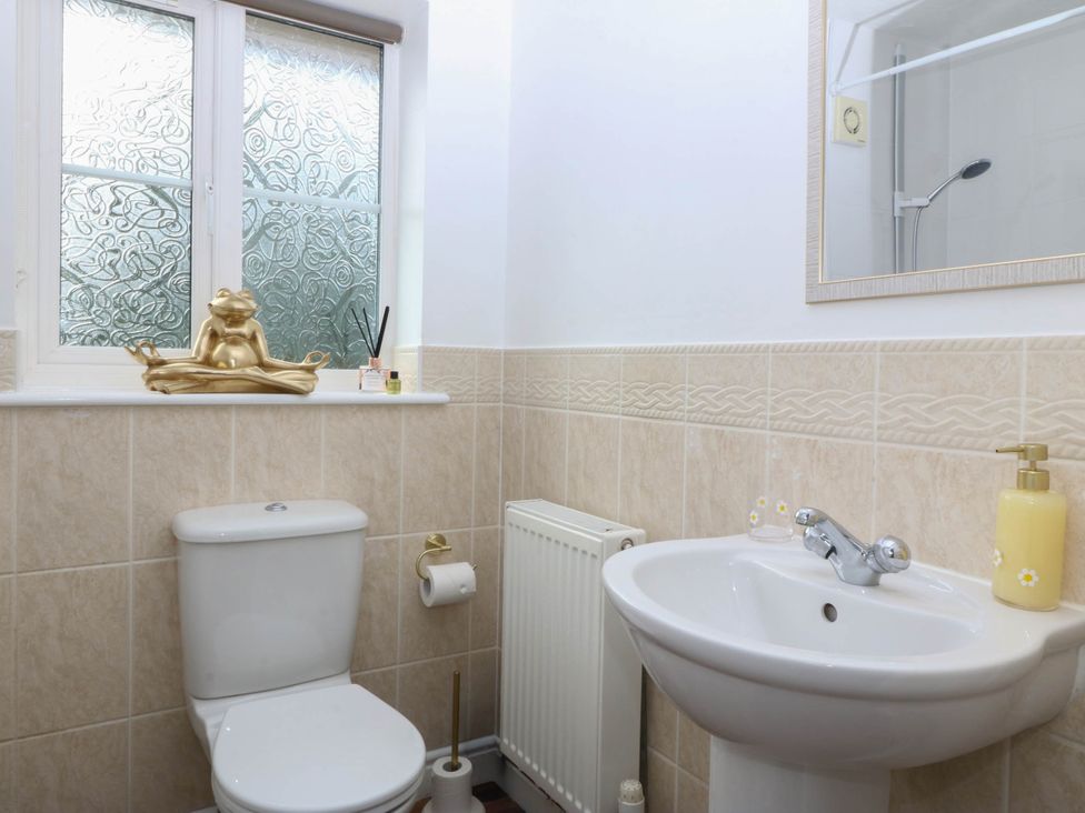 A bathroom with a toilet, washbasin, and decorative items at Meadow View in Kinmel Bay