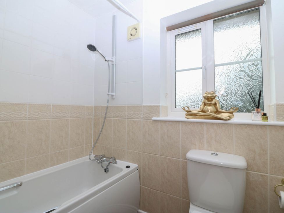 A bathroom with a bathtub, toilet, and a window at Meadow View in Kinmel Bay