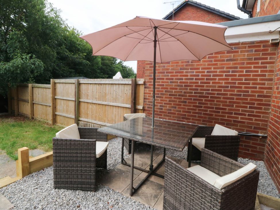 A garden area with a table and chairs under an umbrella at Meadow View in Kinmel Bay