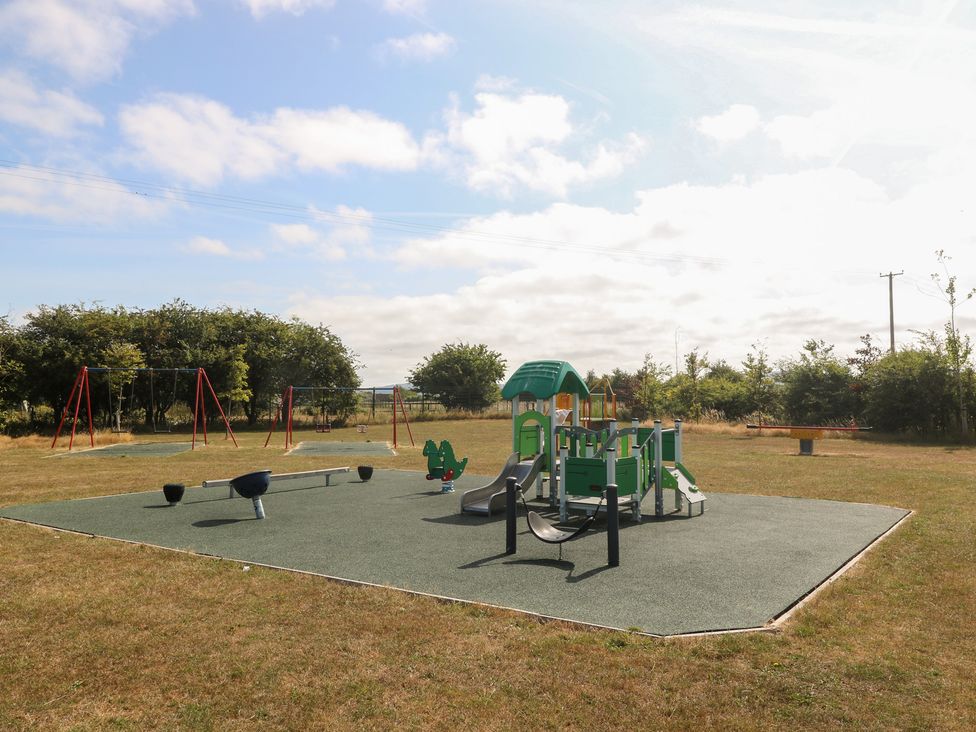 A playground with swings and play equipment at Meadow View in Kinmel Bay