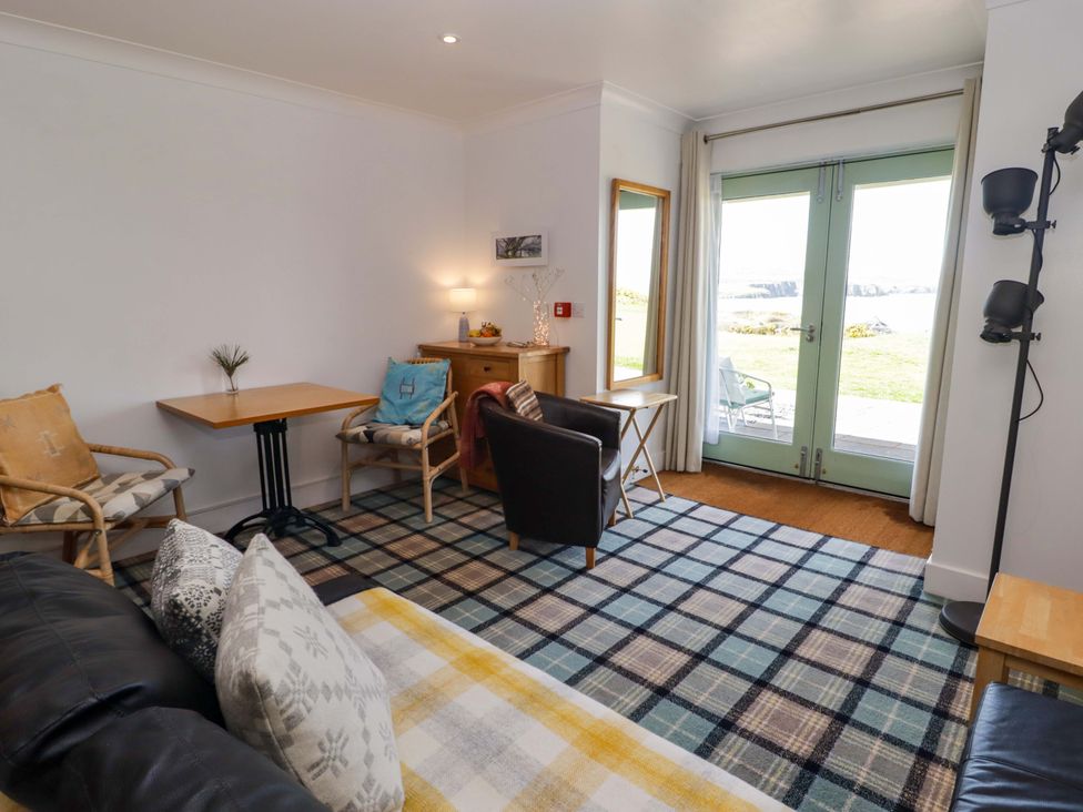 A living room with a sofa, chairs, and a table at Ty Mor in Newport, Pembrokeshire