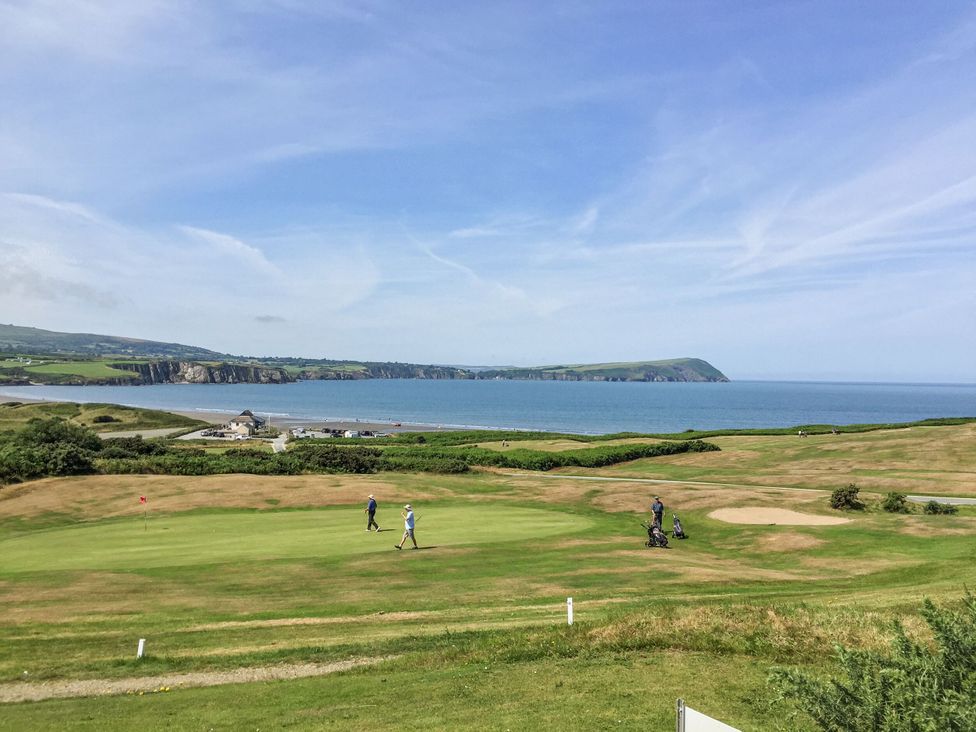 A golf course with golfers near the ocean at Ty Mor in Newport, Pembrokeshire