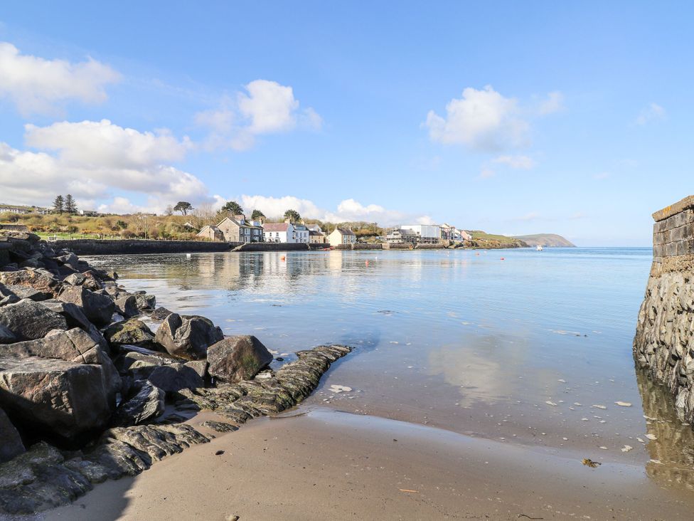 View of a shoreline with buildings along the water at Ty Mor in Newport, Pembrokeshire