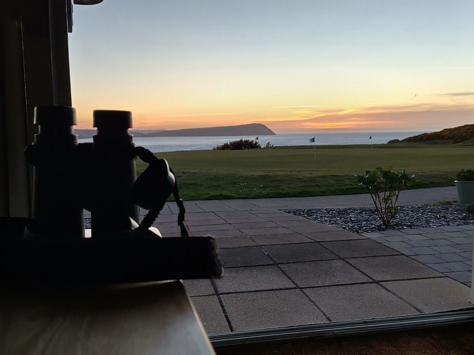 A view of a golf course and ocean with binoculars at Ty Mor in Newport, Pembrokeshire