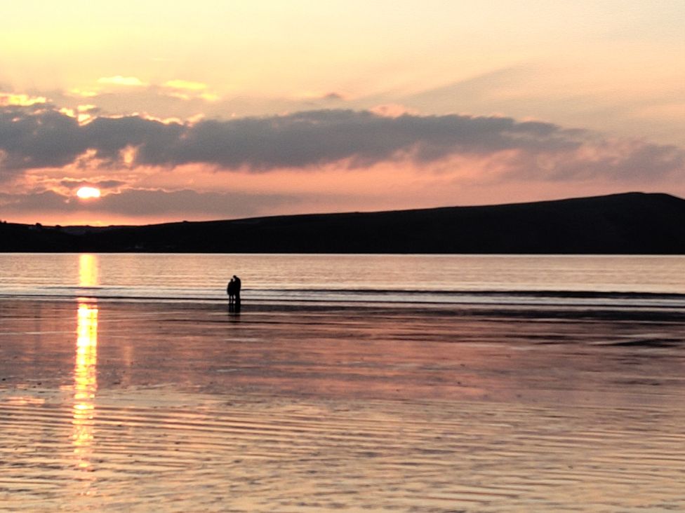 A person standing in water during sunset at Ty Mor in Newport, Pembrokeshire