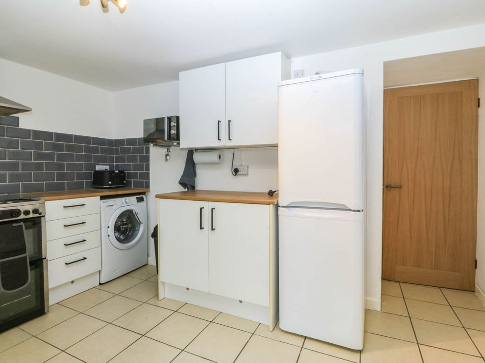 A kitchen with appliances including a fridge and washing machine at Emily Rose Cottage Bangor