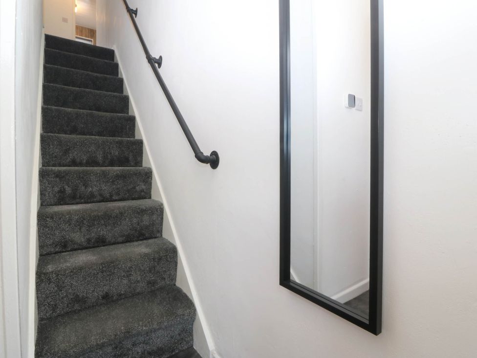 A staircase with a handrail and a mirror at Emily Rose Cottage in Bangor