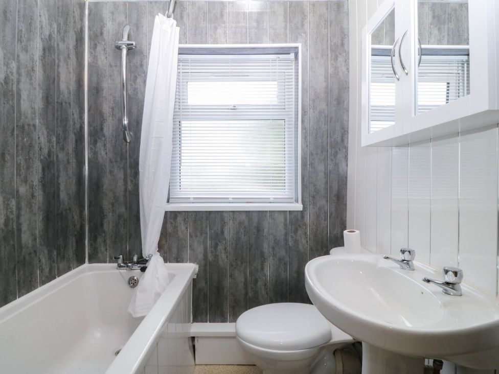 A bathroom with a bathtub, toilet, and sink at Emily Rose Cottage in Bangor